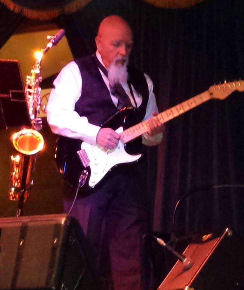 Raul playing guitar on a dimly lit indoor stage