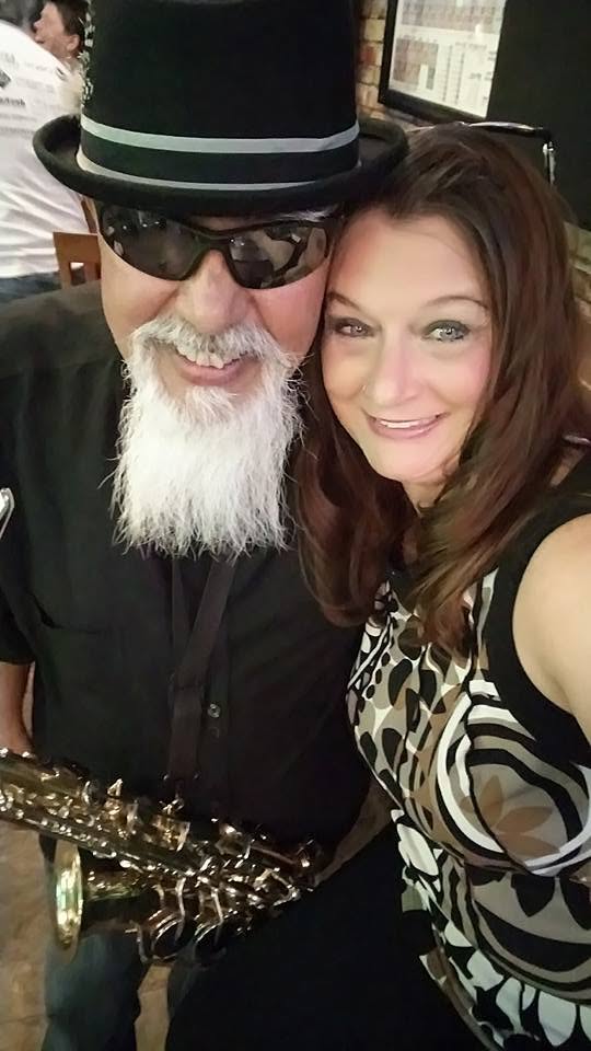 Raul in a top hat with his saxophone beside Laurie at a venue